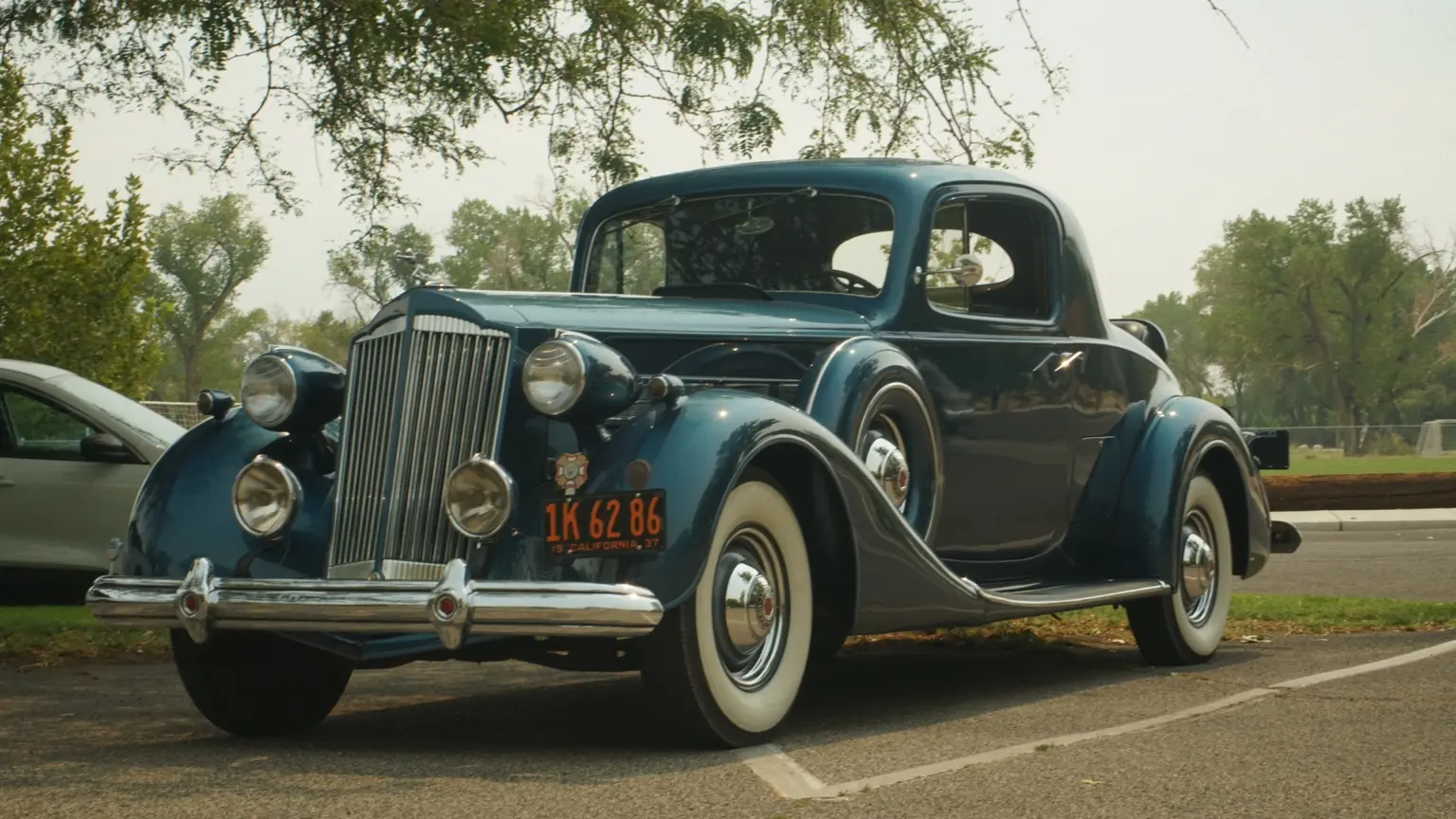 Classic automobile parked beneath leafy trees