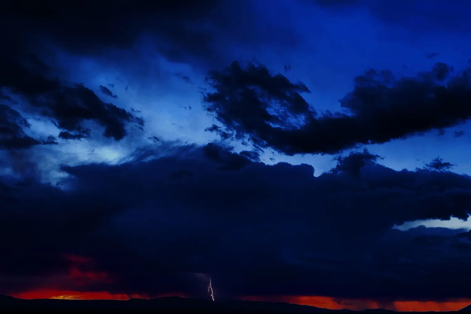 Deep blue storm clouds above a red horizon