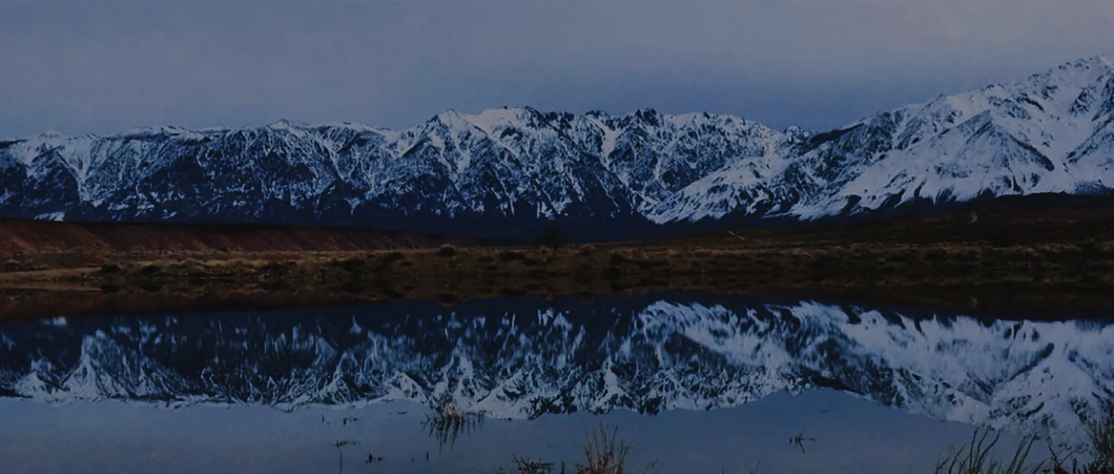 Snow-covered Sierra reflected across still water