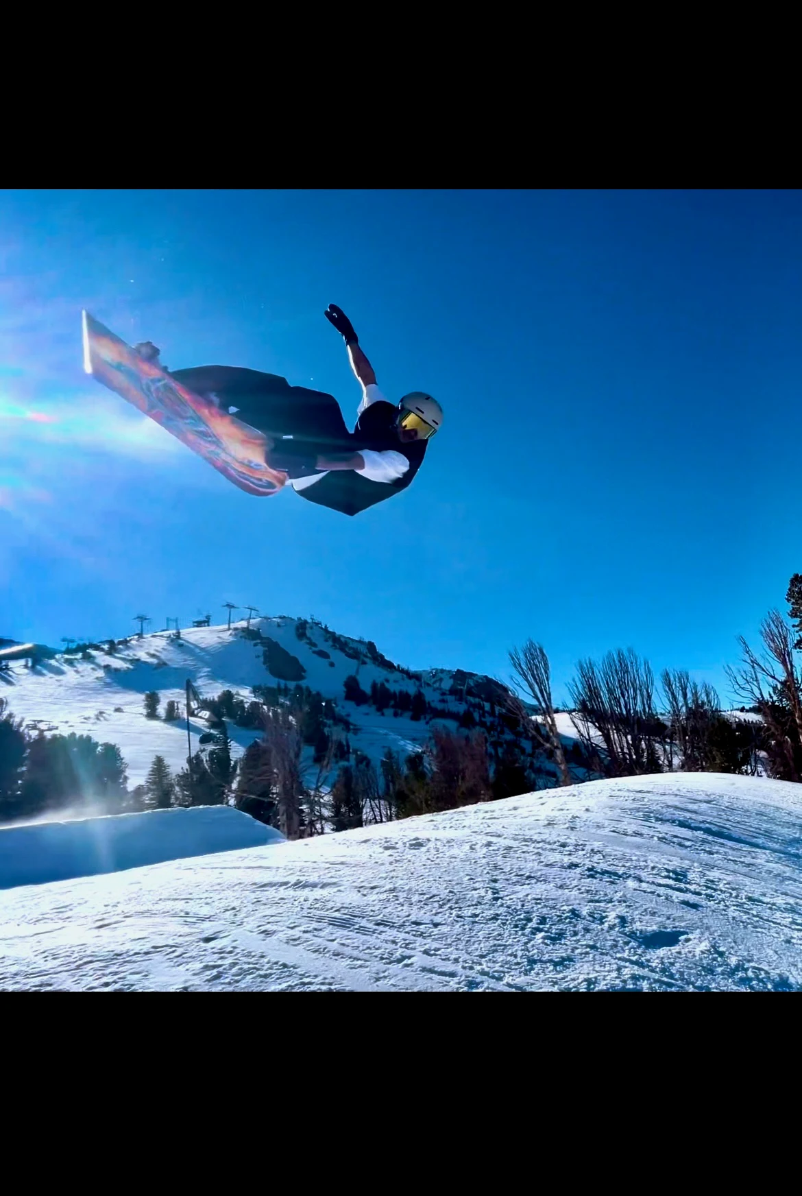 Snowboarder turning in the air against a blue winter sky