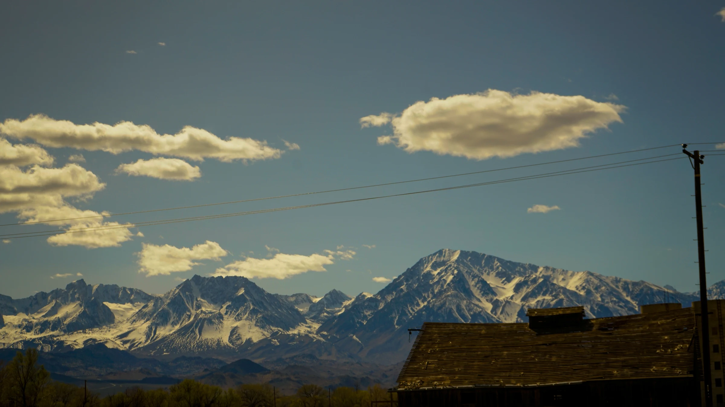 Snow-covered mountain range beyond a weathered rooftop
