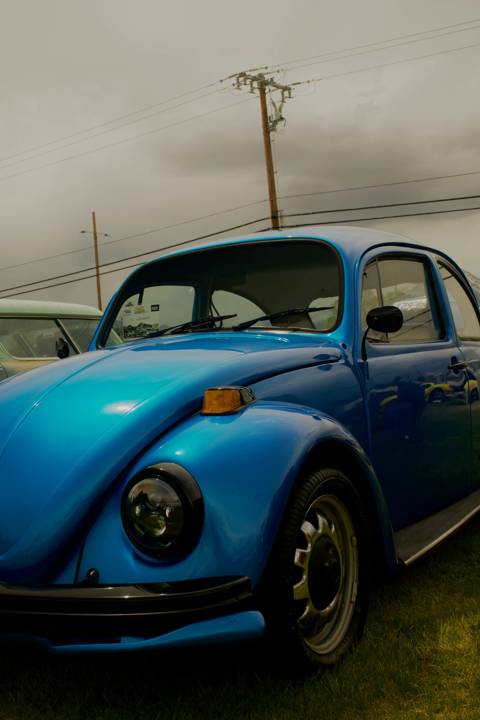 Blue Volkswagen Beetle beneath an overcast sky