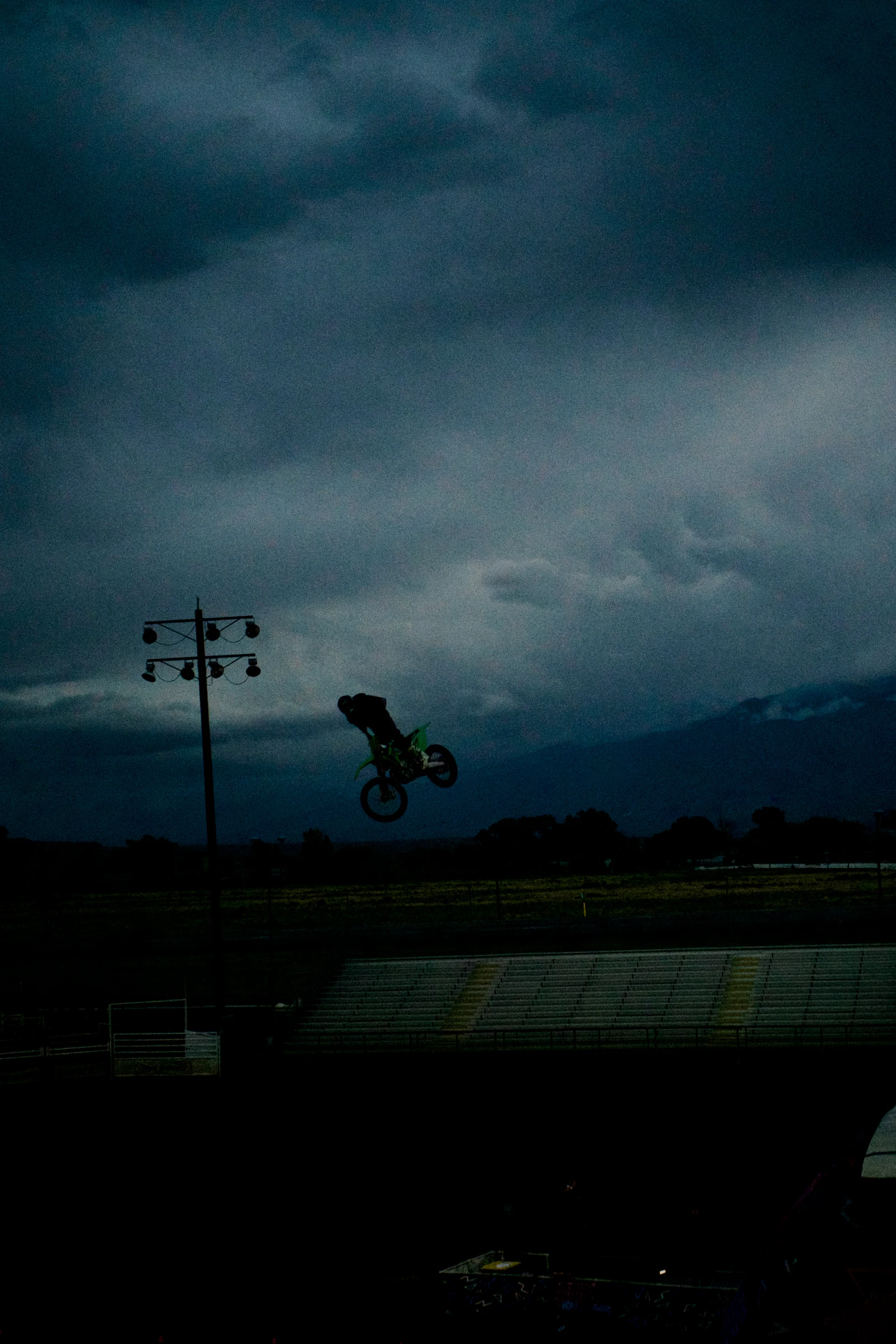 Rider silhouetted above a ramp beneath storm clouds