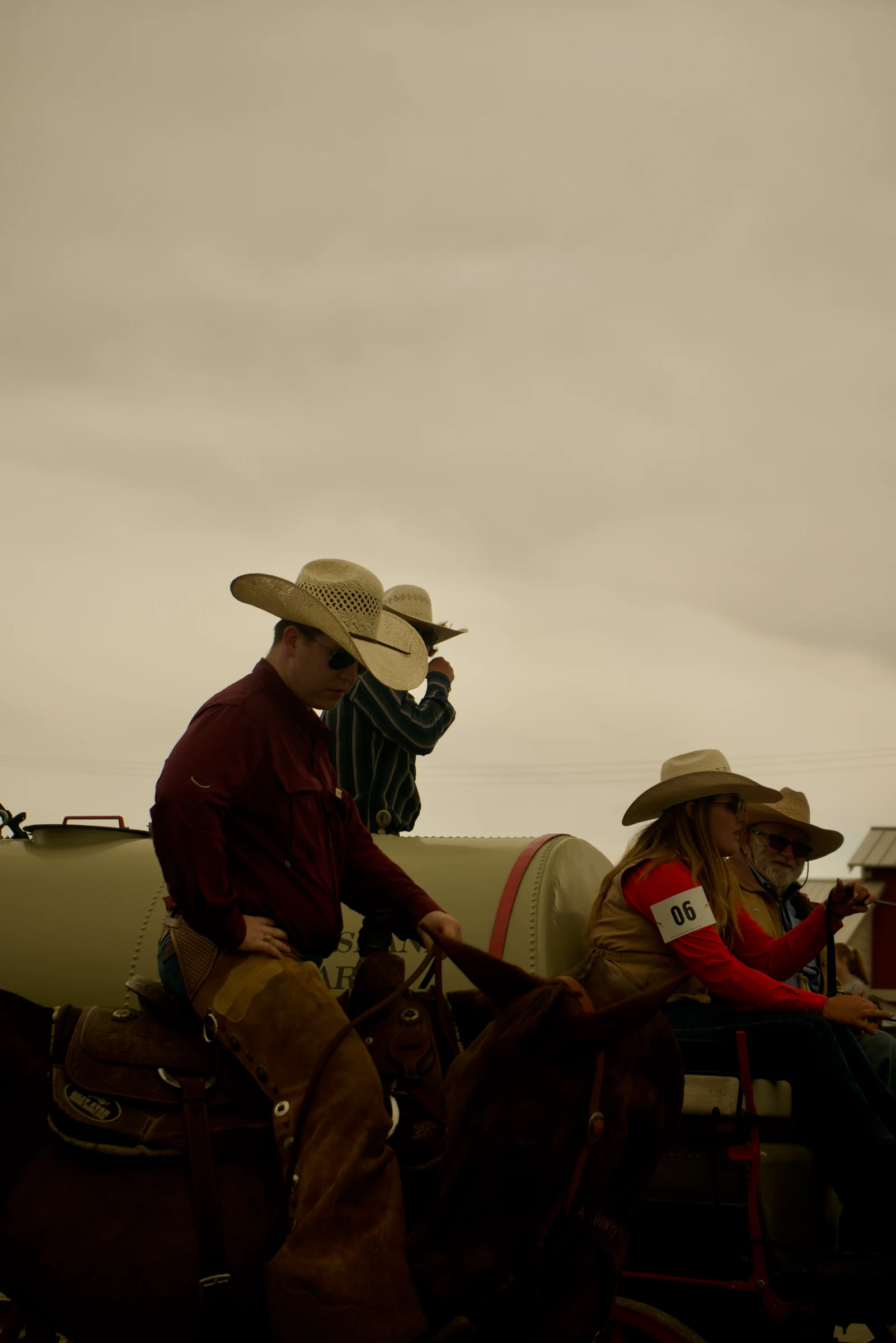 Horseback riders wearing cowboy hats beneath a pale sky
