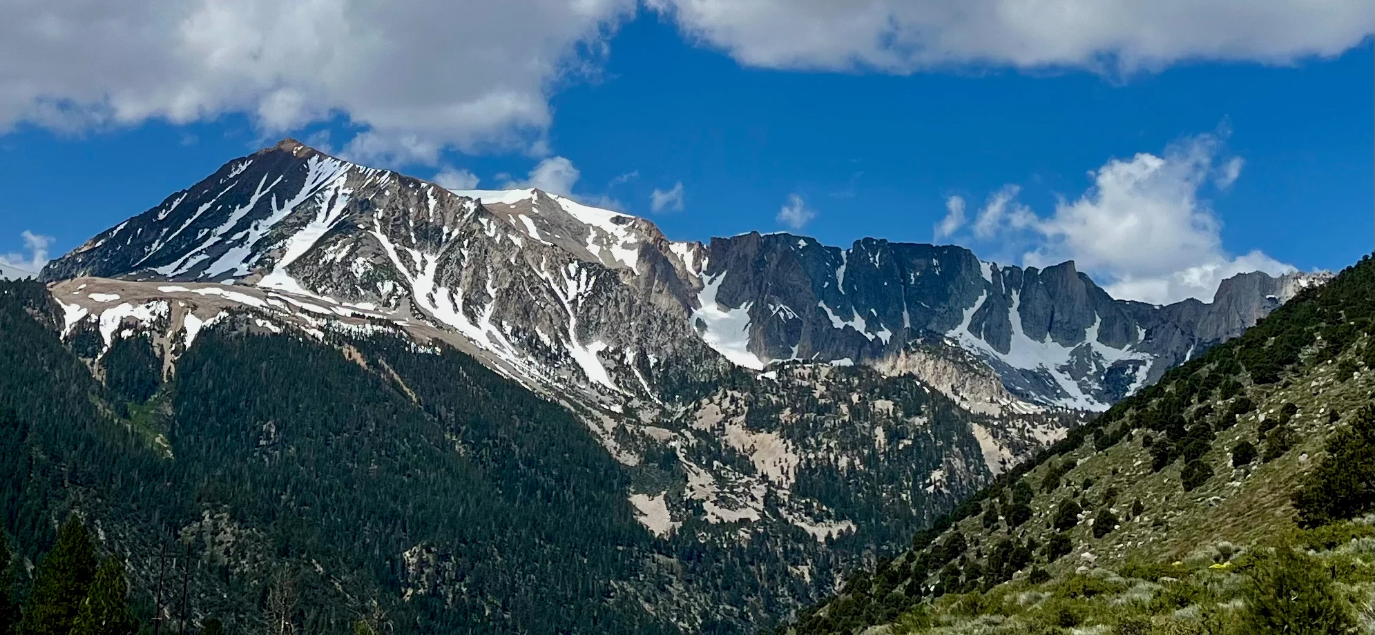 Jagged snow-streaked peaks above a green mountain valley