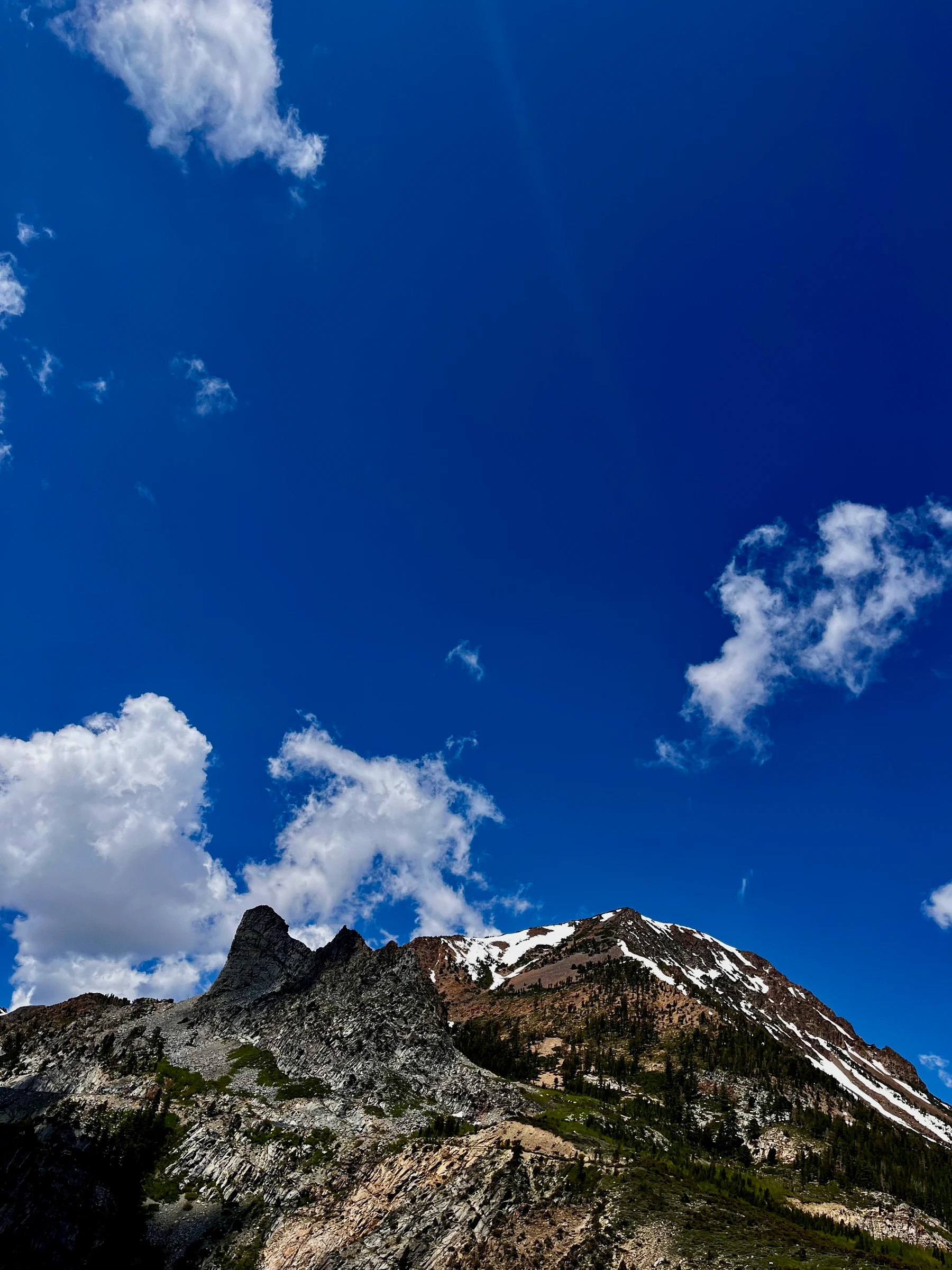 Rocky mountain ridge beneath white clouds and deep blue sky