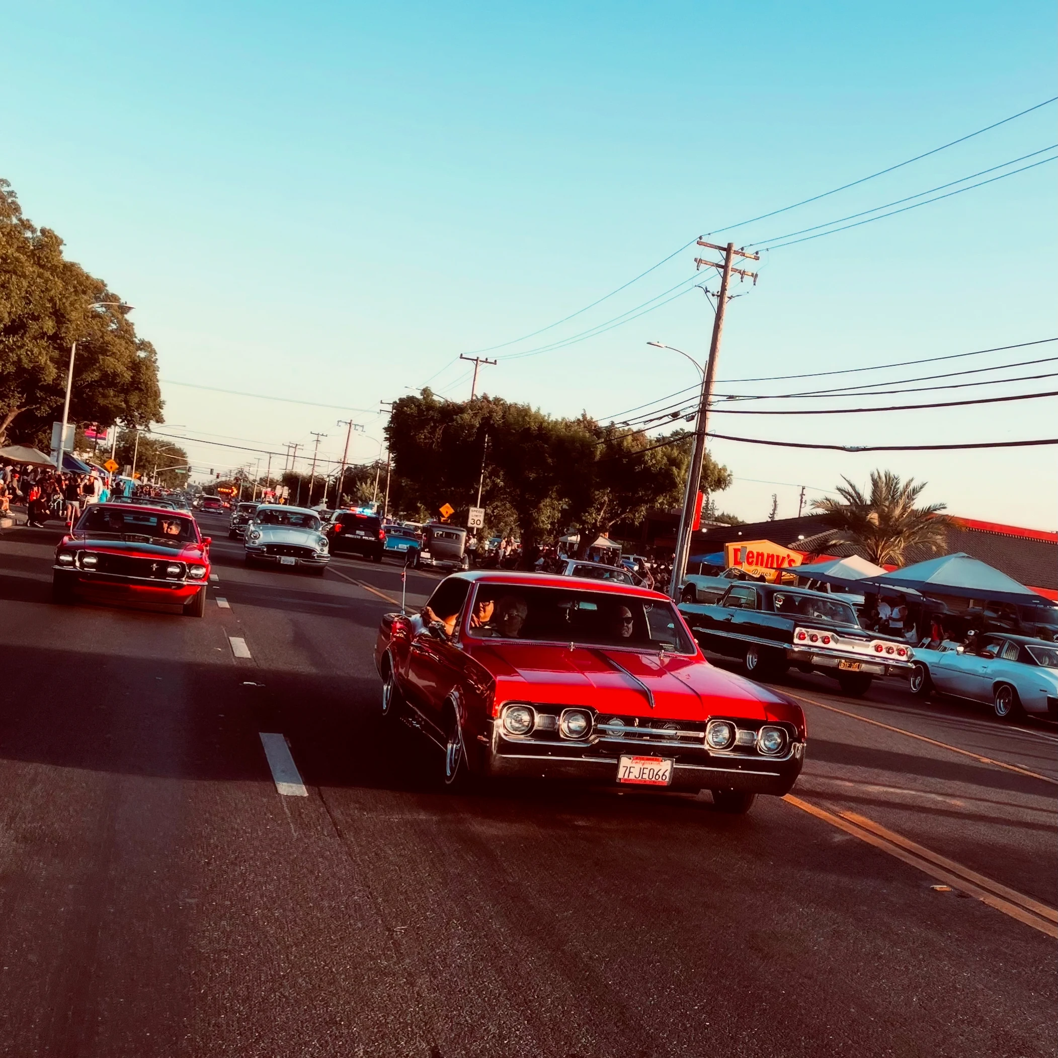 Classic cars cruising along a sunlit town street