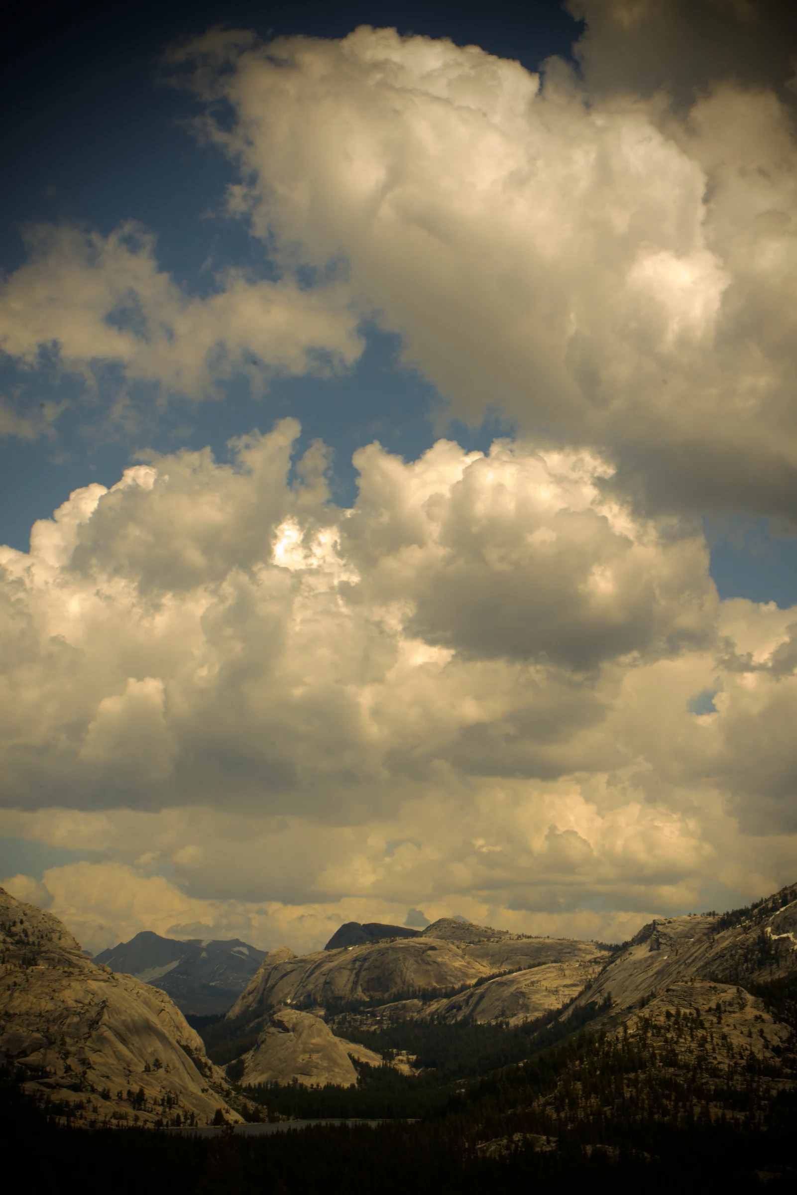 Sunlit storm clouds towering above rocky mountains