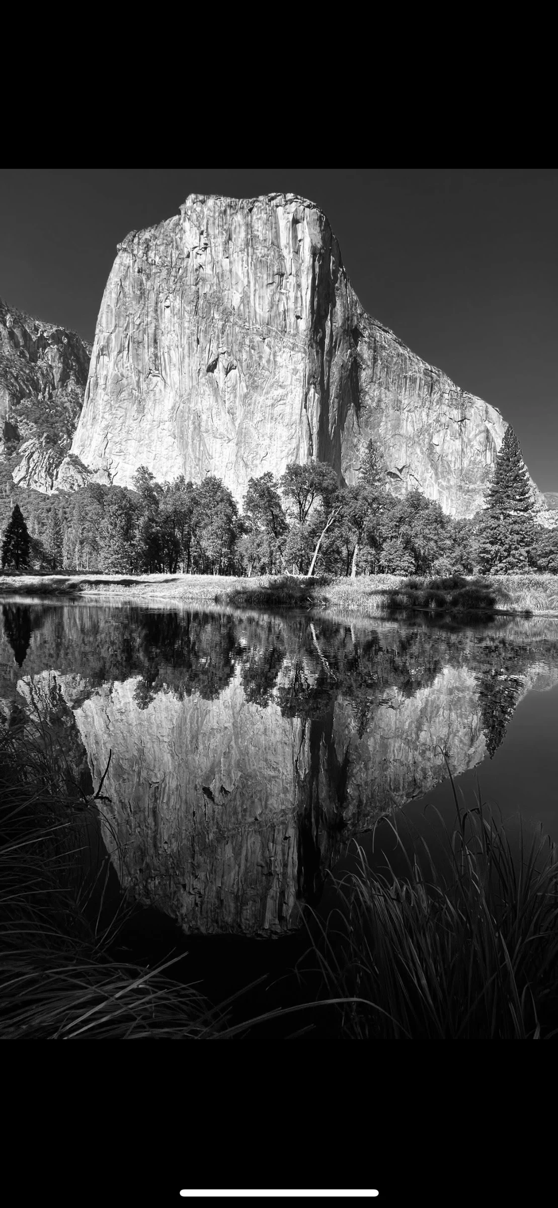 Black-and-white granite cliff reflected in calm water