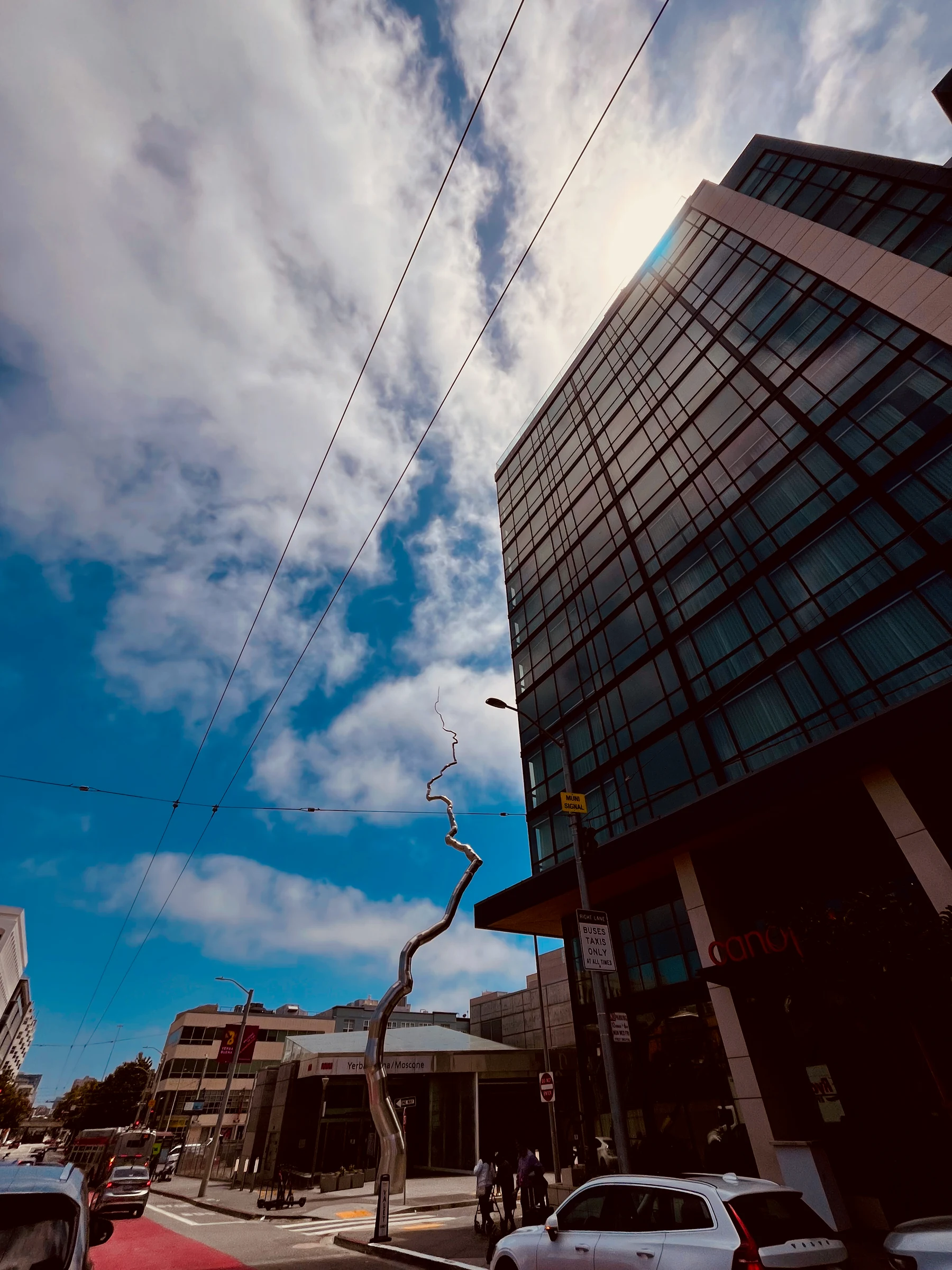 Modern building and street viewed beneath sweeping clouds